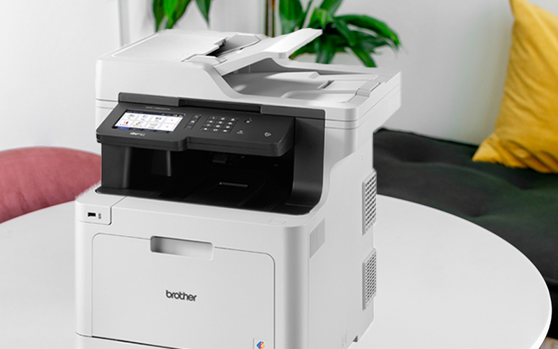 Brother printer sits on table on home office with plant in background
