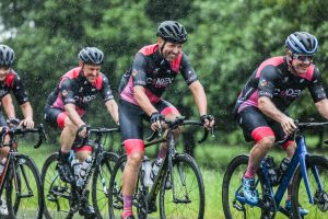 Cyclists riding in the rain with green vegetation in background