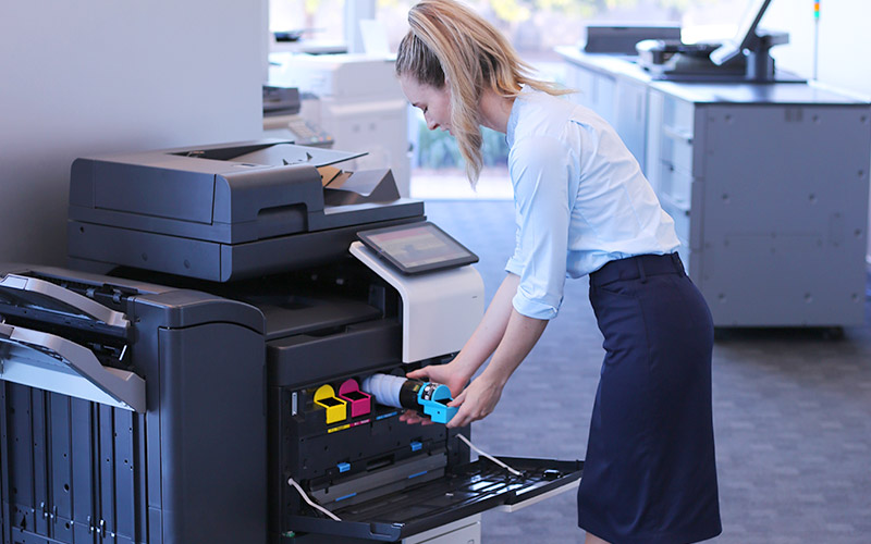 Woman in corporate outfit puts toner into Konica Minolta bizhub C250i