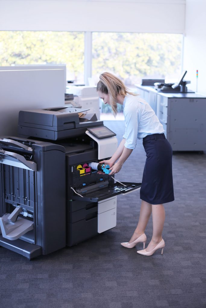 Managed Print Services Document SOlutions worker replacing cyan toner in Konica Minolta bizhub copier