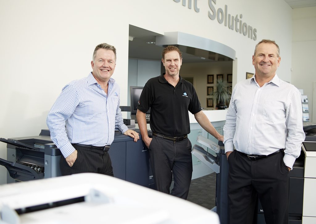 Konica Minolta Gold Coast Document Solutions team members Alan Thompson, Craig McHenry, Colin Wheeler stand smiling in showroom