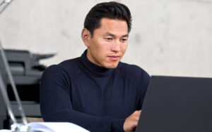 Man sits looking at laptop